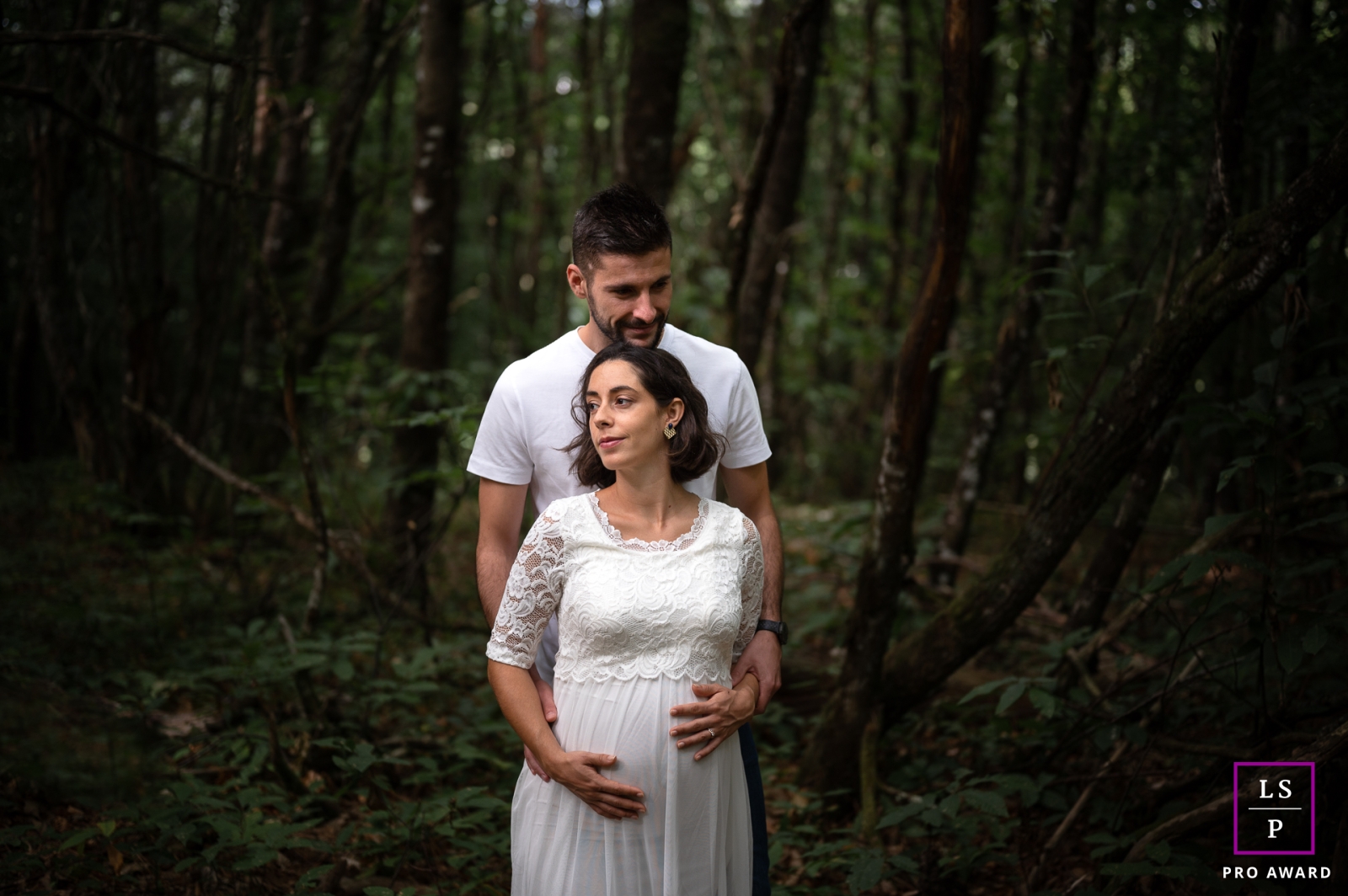 The love between this couple is palpable as they embrace in the forest, with the mom-to-be tenderly cradling her growing baby bump