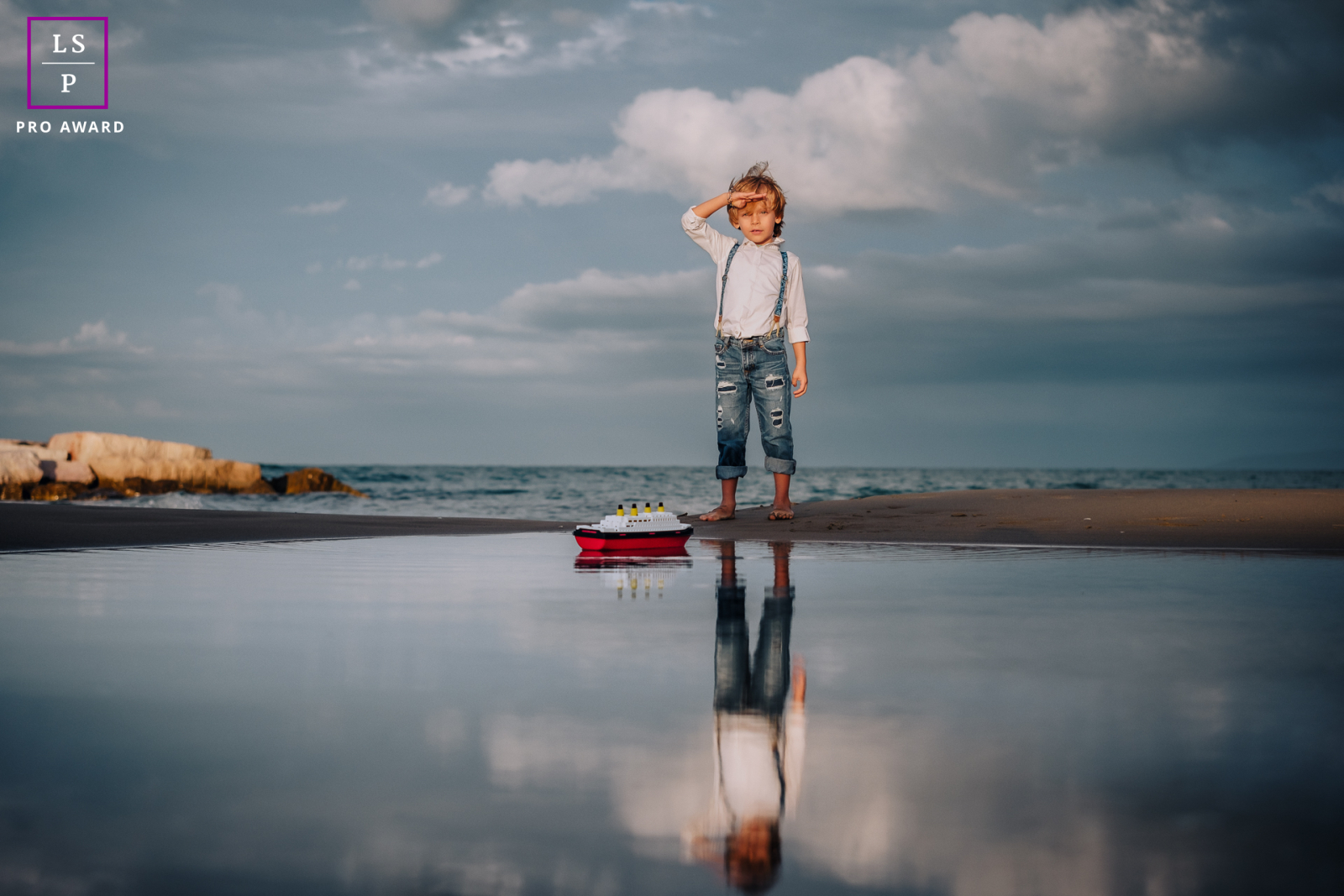 Na Puglia, Itália, um menino brinca alegremente com seu modelo do navio Titanic, banhado pelos tons quentes de um pôr do sol de outono, capturando seu amor por navios contra o deslumbrante céu noturno.