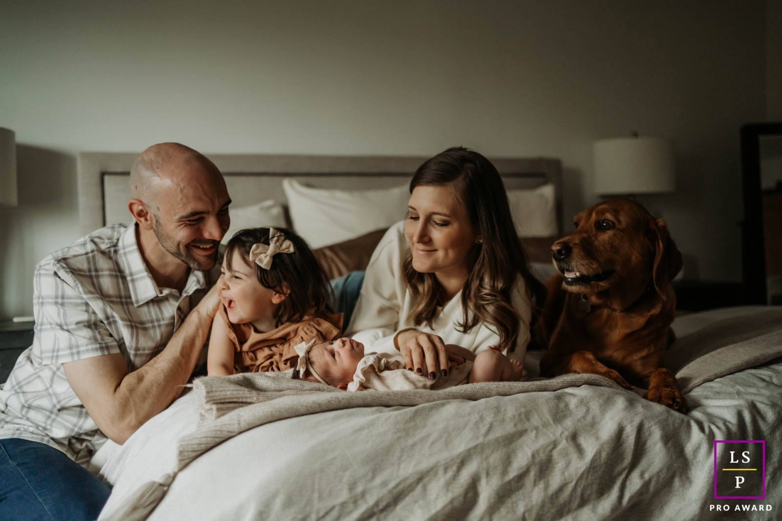 Uma encantadora família de quatro pessoas, posando sem esforço em uma cama, captura a essência de seu estilo de vida na cidade de Portland, Oregon
