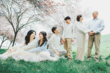 In San Ramon, California, three generations gather beneath blooming trees, each pair sharing its own quiet interaction. The soft spring light and layered composition give the portrait warmth, tenderness, and a gentle sense of family continuity.