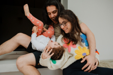 A family laughs together while playfully tickling their young daughter during a joyful moment at home in Morlaix, France.