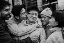 A family gathers in a close embrace, sharing kisses, smiles and emotion during a heartfelt goodbye together in Boston.