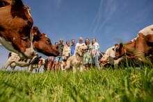 A family gathers with their dog among curious cows in a grassy pasture on their farm in Schipluiden, the Netherlands.