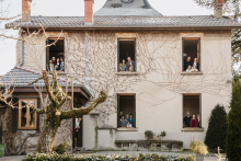 A multigenerational family gathers in separate windows of their family home during a winter lifestyle session in Caluire-et-Cuire, Rhône, France.