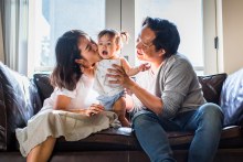 A mother kisses her smiling young child as the father looks on affectionately during a relaxed family moment in Pasadena, California.