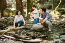A family enjoys playful time together beside a creek during a relaxed outdoor lifestyle photography session California.