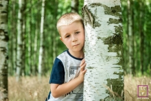 A Warsaw portrait of a kid cuddling up to a birch tree in a forest in Mazowieckie