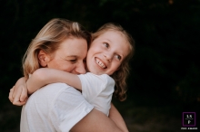 Portrait de style de vie captivant : une étreinte mère-fille réconfortante dans l'Oise, France Un portrait de style de vie réconfortant capturant l'étreinte tendre d'une fille envers sa mère sur un fond noir saisissant dans l'Oise, en France