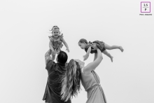 This lifestyle portrait from Yarmouth, Massachusetts captures pure family bliss as mom and dad raise their two daughters in the air, celebrating love and unity in a single, uplifting shot