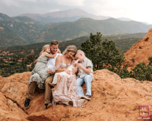In Colorado Springs, CO, a family shares a cuddle on a rock at Garden of the Gods, surrounded by stunning natural beauty.