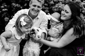A black-and-white photo shows a toddler kissing the family's dog. The scene is tender, with love radiating from every family member's face in Chatham, Massachusetts.