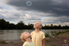 In Haute-Garonne, siblings are looking up at a floating soap bubble. The portrait captures the children's innocent and joyful fascination.