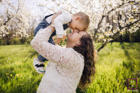 In Lyon, France, a mother lifts her young son into the air. They are face to face, heads touching, with warm, backlit sunshine creating a soft, glowing outline around them.