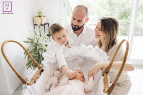 In Lyon, France, a newborn baby lies in a crib while mom and dad look on lovingly. Their eldest son gently interacts with his baby sister, and the parents admire the sweet sibling connection.