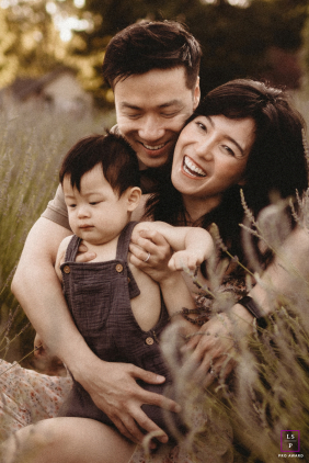 In Richmond Hill, ON, parents hold their one-year-old child close. The mother beams with a radiant smile touched by memory, reflecting on their journey from the NICU to this heartfelt family embrace.