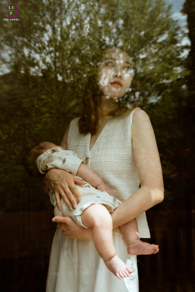 Photographed through a window in Toronto, a mother cradles her newborn as they prepare to leave for a new city. The image captures tenderness, anticipation, and the bittersweet start of a new adventure.