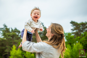 In Hilversum, The Netherlands, a toddler bursts with laughter as his mom lifts him high above the treeline. His joyful expression and the soaring view capture a sense of freedom and delight.