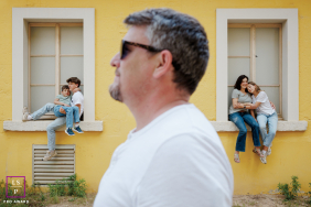 In Paris, a family portrait features dad in the foreground in profile, while the rest of the family sits on window sills behind him. The composition highlights familial connection with a stylish, layered arrangement.