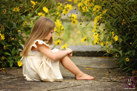 At Blackpool's Stanley Park in the UK, a young girl hides among flowers beneath a yellow arch overhead.