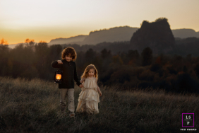 Portland Children Carry A Warm Lantern Across The Hillside At Dusk In Portland, Oregon, children carry a lantern across a hillside at dusk, illuminated by warm sunset tones as evening settles over the landscape.