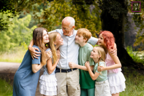 Overijssel Grandfather Hugs Five Grandchildren: A Timeless Outdoor Portrait of Natural Love In Overijssel, Netherlands, a grandfather hugs all five of his grandchildren at once outdoors, surrounded by trees and natural scenery.