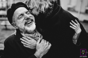 In Paris, France, a black-and-white portrait captures a couple laughing and embracing in the streets, his expression filled with emotion.