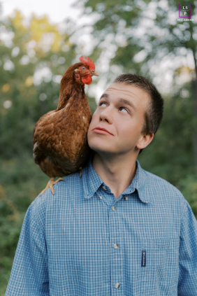 In Port Washington, Wisconsin, a man and a chicken lock eyes in a humorous and slightly awkward faceoff, his expression filled with curiosity.