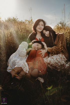 Sunlit Autumn Field: Mother's Pride As Eldest Daughter Prepares To Leave In Oakville, Ontario, a mother gathers her two daughters close in a sunlit autumn field, her face reflecting pride and nostalgia as her eldest gets ready to set off on her own.