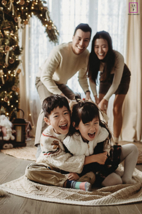 Oakville Family Joyfully Gathers By Their Handmade Ornament Christmas Tree In Oakville, Ontario, a family gathers by a Christmas tree adorned with handmade ornaments, their joyful smiles adding extra warmth to the festive scene.
