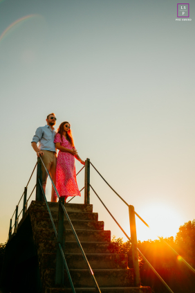 In Mauguio, France, a couple stands at the top of a staircase during sunset, bathed in the warm glow of the evening light.