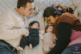 New Jersey Husband Gazes Lovingly At Wife Snuggling Newborn Twins In Bergen County, New Jersey, a husband lovingly gazes at his wife as they snuggle together with their newborn twins.