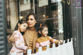 DUMBO Coffee Shop Reflections: Mother And Daughters Share Sweet New York Time In DUMBO, Brooklyn, a mother and daughters enjoy time together inside a coffee shop, captured from outside through reflective glass in downtown New York City.
