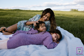 Nashville Mother And Daughters Lie Together Enjoying Peaceful Outdoor Moments In Nashville, Tennessee, a mother and her daughters lie together on a blanket in the grass, enjoying time outdoors.