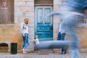 Bayonne Family Portrait: Ancient Stone and Childhood Motion Blur Family poses near an old building in Bayonne, France; one child runs past shown in motion.