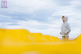 Child in a striped hoodie stands thoughtfully on the sandy beach at Biarritz Plage.