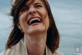 Smiling woman, Indre, laughing joyously by the sea shore for a lifestyle portrait.