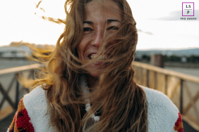 A joyful woman standing by the sea in Leucate, laughing brightly as she looks toward the camera. 