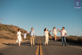 Joyful Family Portrait With Grandparents Posing On A Bright Yellow Road Line Six family members, including grandparents, pose joyfully on a road, split by a bright yellow dividing line.