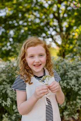 Joyful girl in Chicago holding a wildflower, smiling warmly for a bright, authentic lifestyle portrait