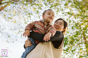 Low Angle Delight: Mother Twirling Happy Young Son In Chicago Chicago lifestyle portrait: A happy mother joyfully twirling her young son, captured from a low angle emphasizing pure delight.