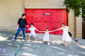 San Francisco Family Portrait: Steep Street Stroll, Hands Held, Love Upward A family portrait in San Francisco, California, features mom and dad holding their children’s hands in a line while standing on a steep urban sidewalk.