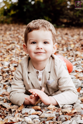 This little gentleman’s dapper jacket offers a witty contrast to the crunch of autumn leaves and river stones. The low perspective masterfully brings us into his charming, earth-bound world of play.