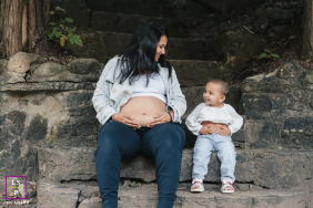 In Toronto, this toddler proudly imitates her expecting mother by lifting her shirt while they sit together on the stone steps. The mirrored gestures and shared smiles give the photograph humor, tenderness, and wonderfully playful family connection.
