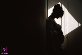 In Châteauroux, an expecting mother stands quietly within a triangle of window light, her silhouette carrying both strength and vulnerability. The dramatic shadows and minimalist composition transform the image into something deeply intimate.