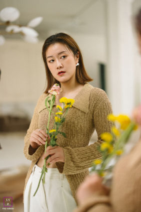 In Chicago, Illinois, the young woman studies her reflection while holding delicate spring flowers close to her chest. The soft tones and mirrored composition give the portrait elegance, introspection, and a gentle sense of renewal.