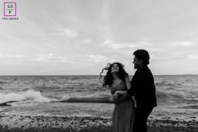 A couple breaks into laughter beside the water as the wind catches her curly hair during a playful session in Toronto.