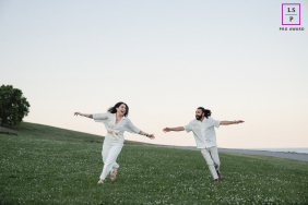 A couple runs toward each other with arms outstretched across a grassy field, sharing a playful and energetic session in Toronto.