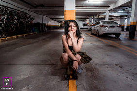 A woman crouches along a painted line in a parking garage, surrounded by parked cars and urban details in São Paulo, Brazil.