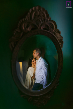 A couple shares a quiet embrace, their reflection framed within an ornate antique mirror during an intimate session in Curitiba, Brazil.