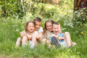 Four Siblings Cuddle And Laugh Together In Tall Grass In Overijssel Four siblings cuddle and laugh together while sitting in tall grass during a relaxed outdoor family session in Overijssel, Netherlands.